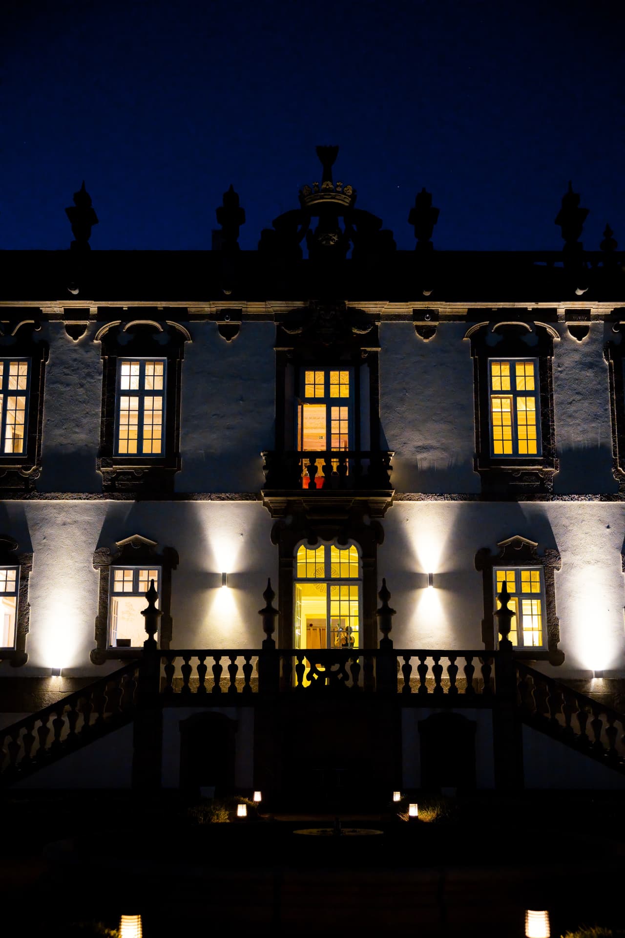 The baroque facade of Palácio do Freixo uplit at night, warm windows glowing against a deep blue sky