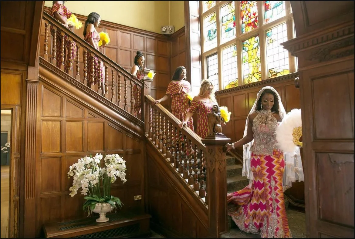 Guests in traditional dress descending a stained-glass stairwell