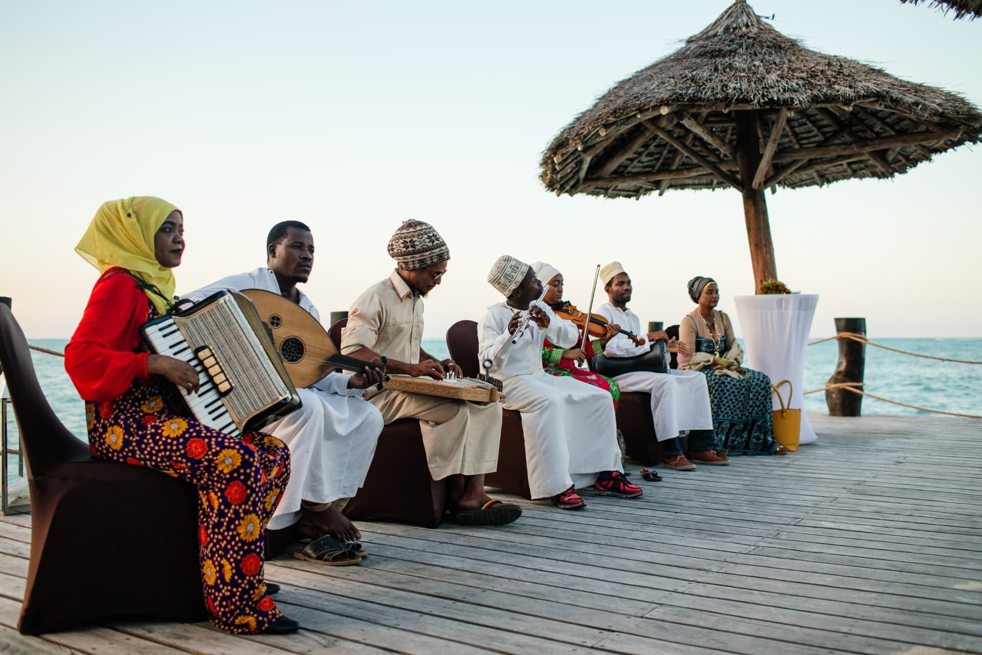 Taarab musicians playing accordion, oud, qanun and violin on a deck over the ocean at sunset in Zanzibar
