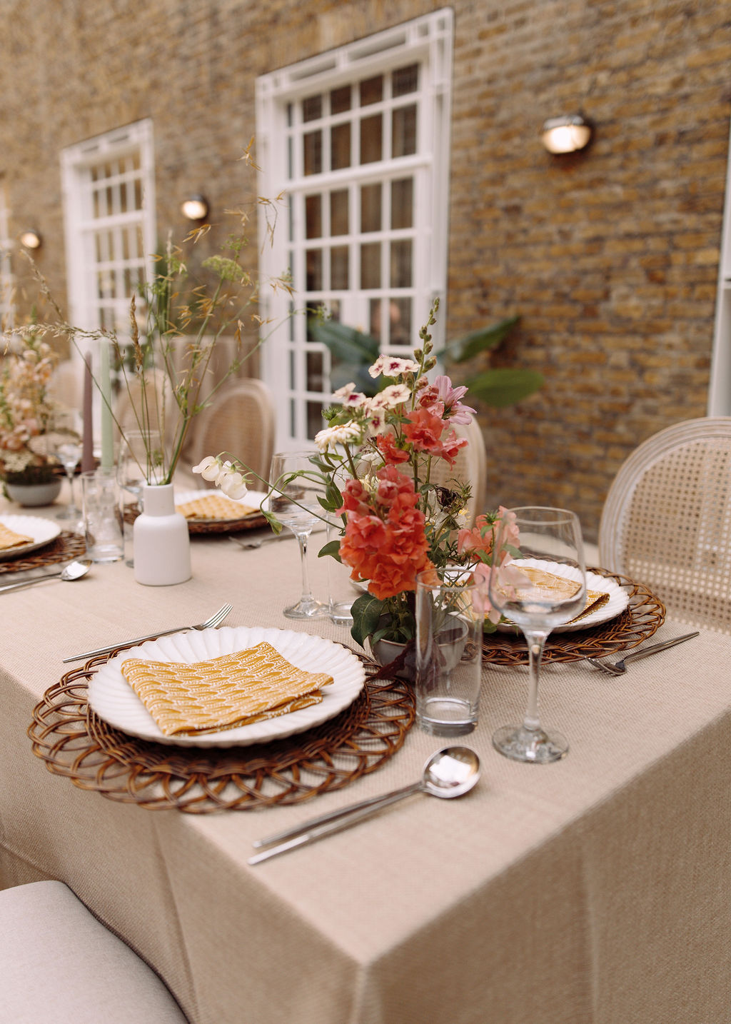 Place setting with a woven charger, fluted plate and gold-printed napkin beside garden florals