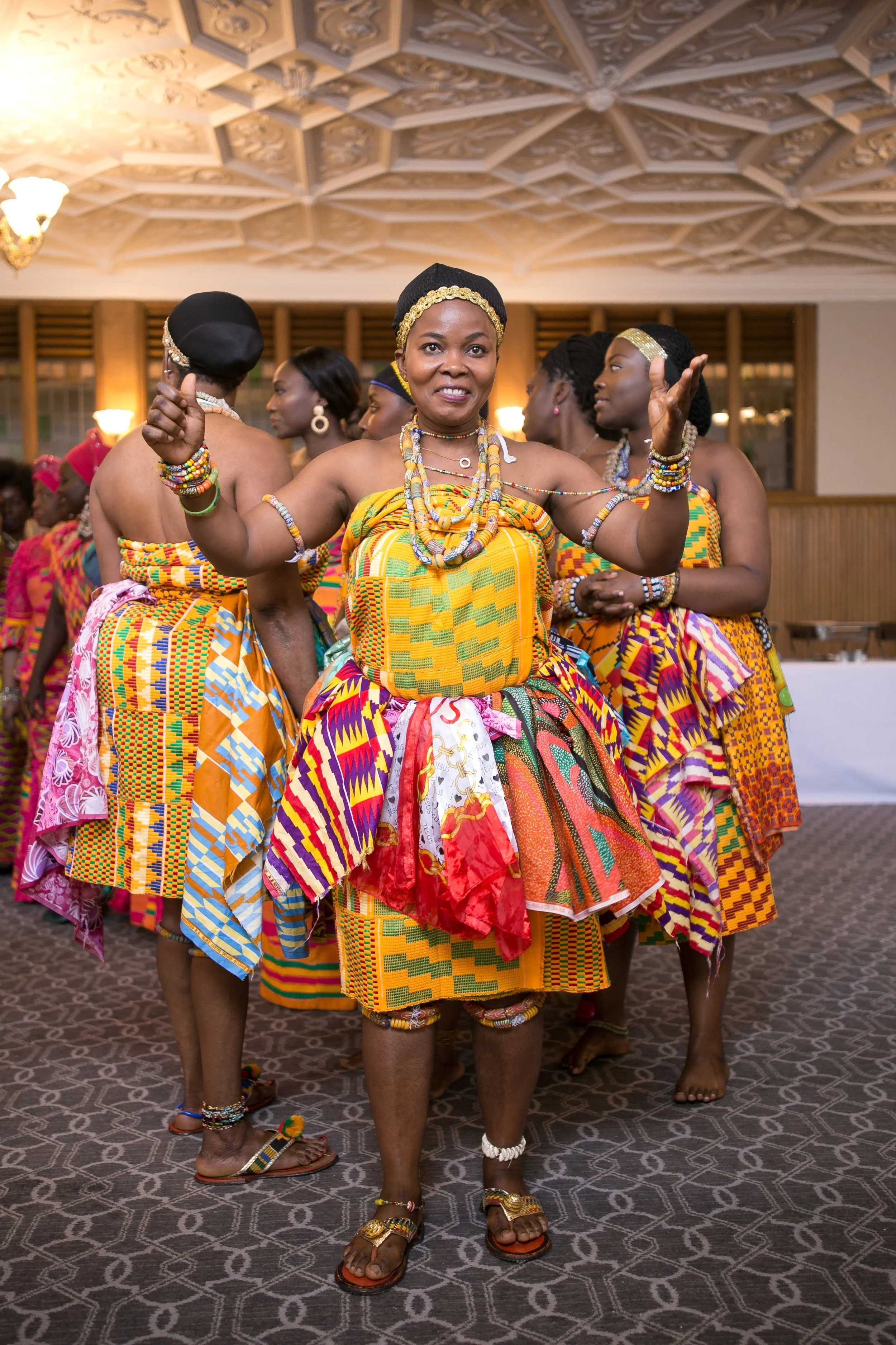 Dancers in Ghanaian kente and headwraps mid-performance
