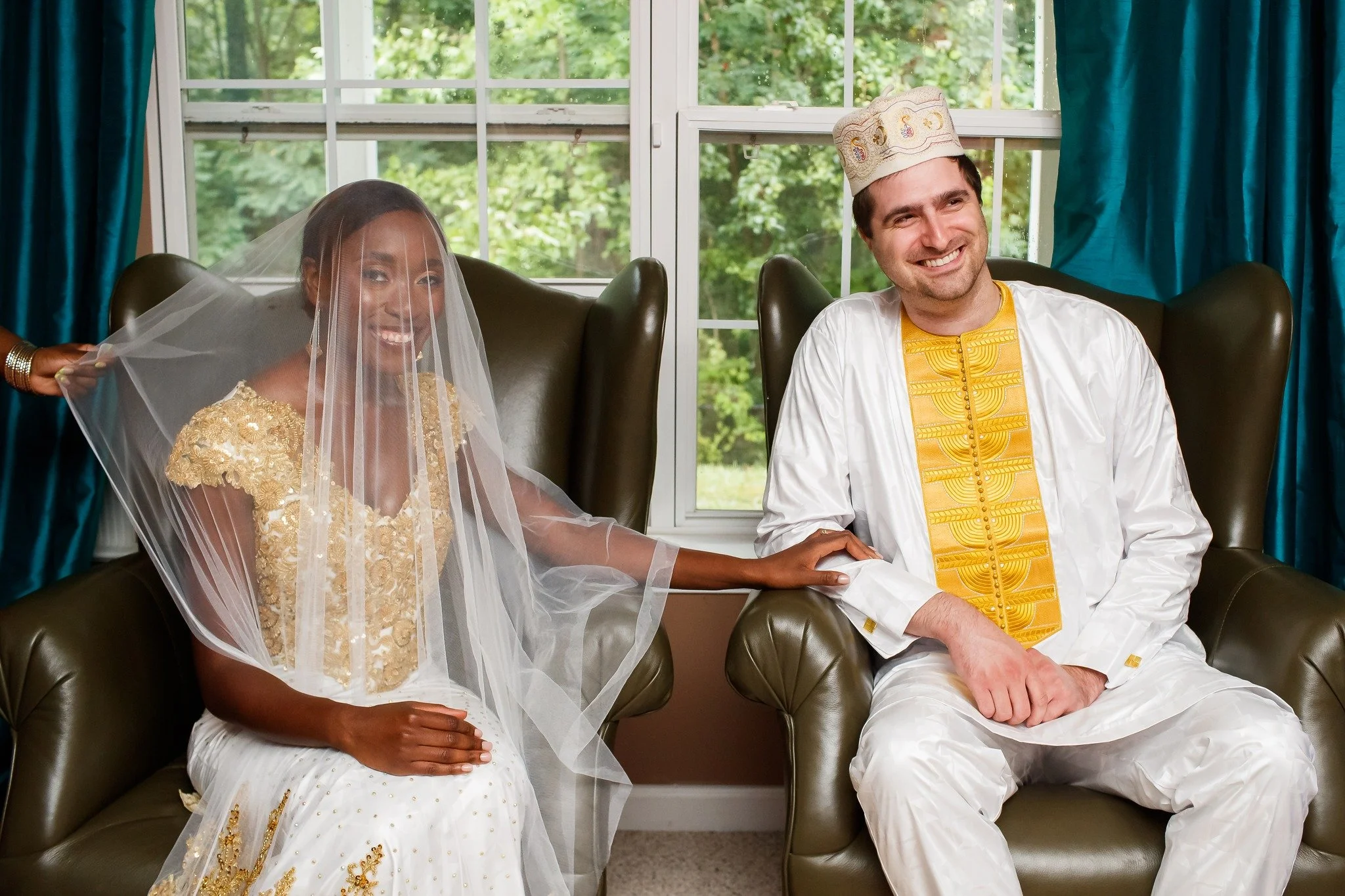 Bride in a gold and white veil seated beside the groom in an embroidered kaftan during a traditional ceremony