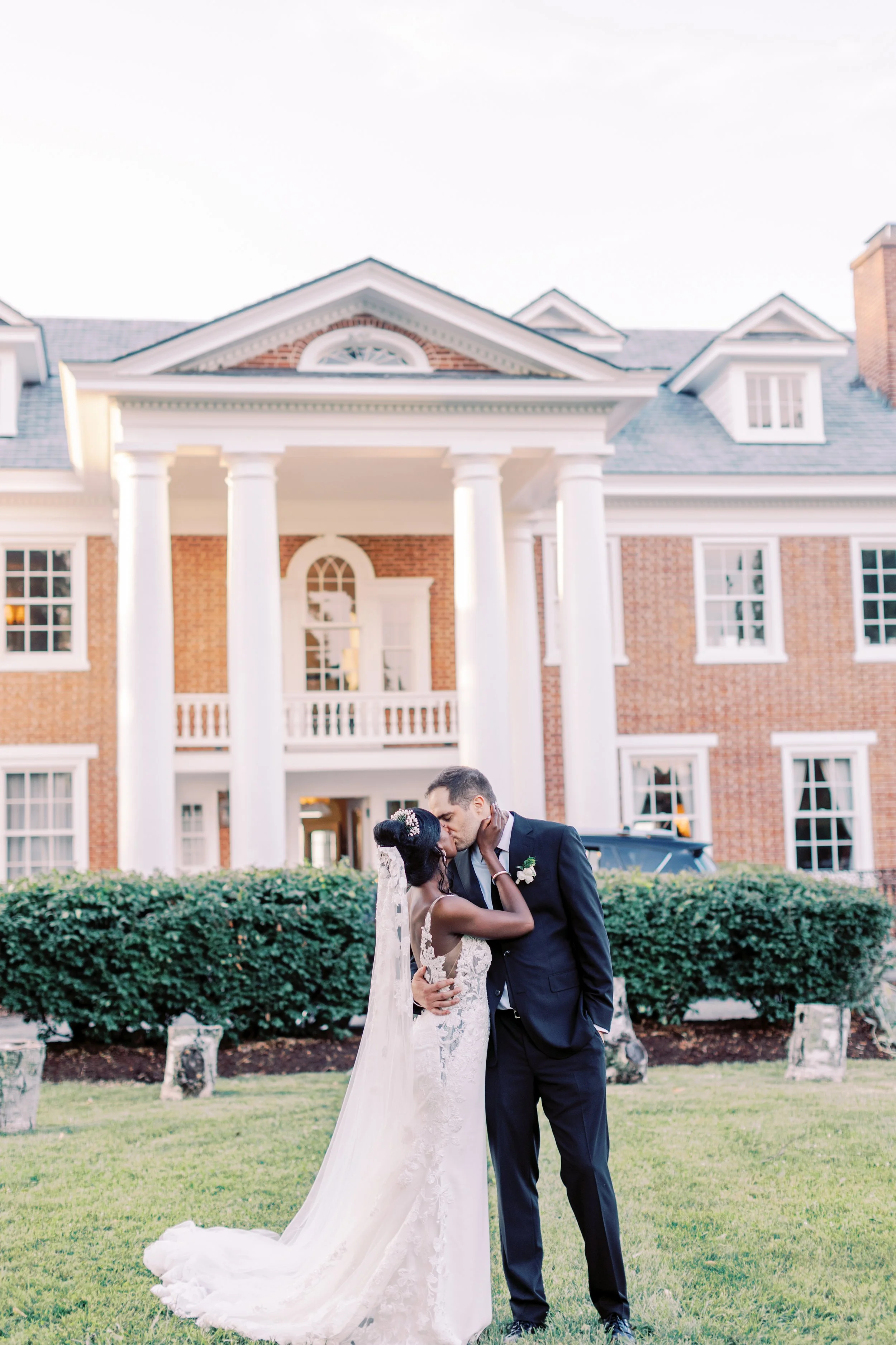 Bride and groom before the columned brick facade of a Virginia manor house