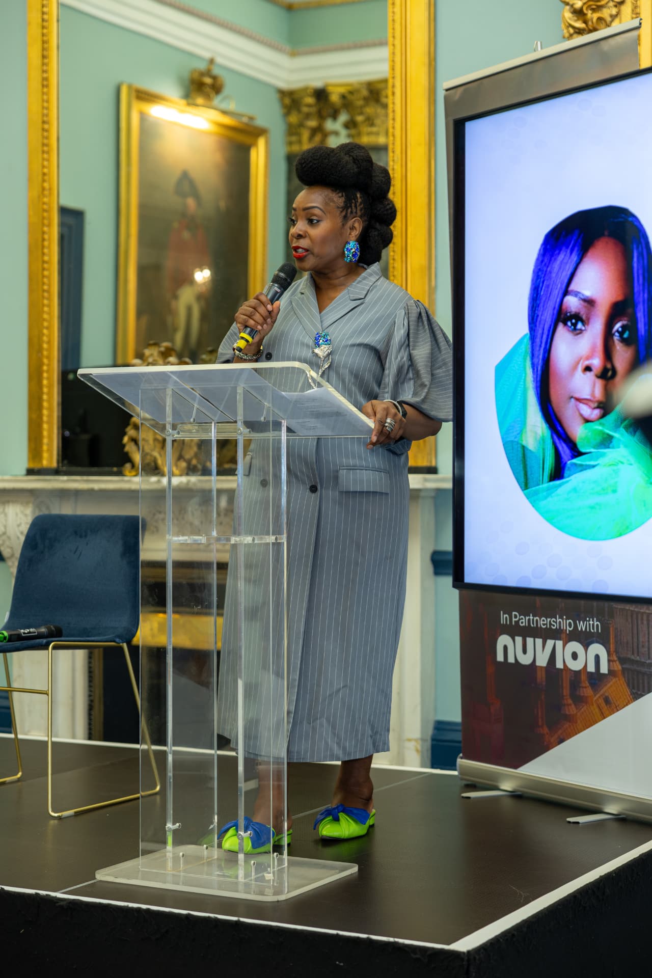 A speaker delivering the keynote from a lectern at the Institute of Directors