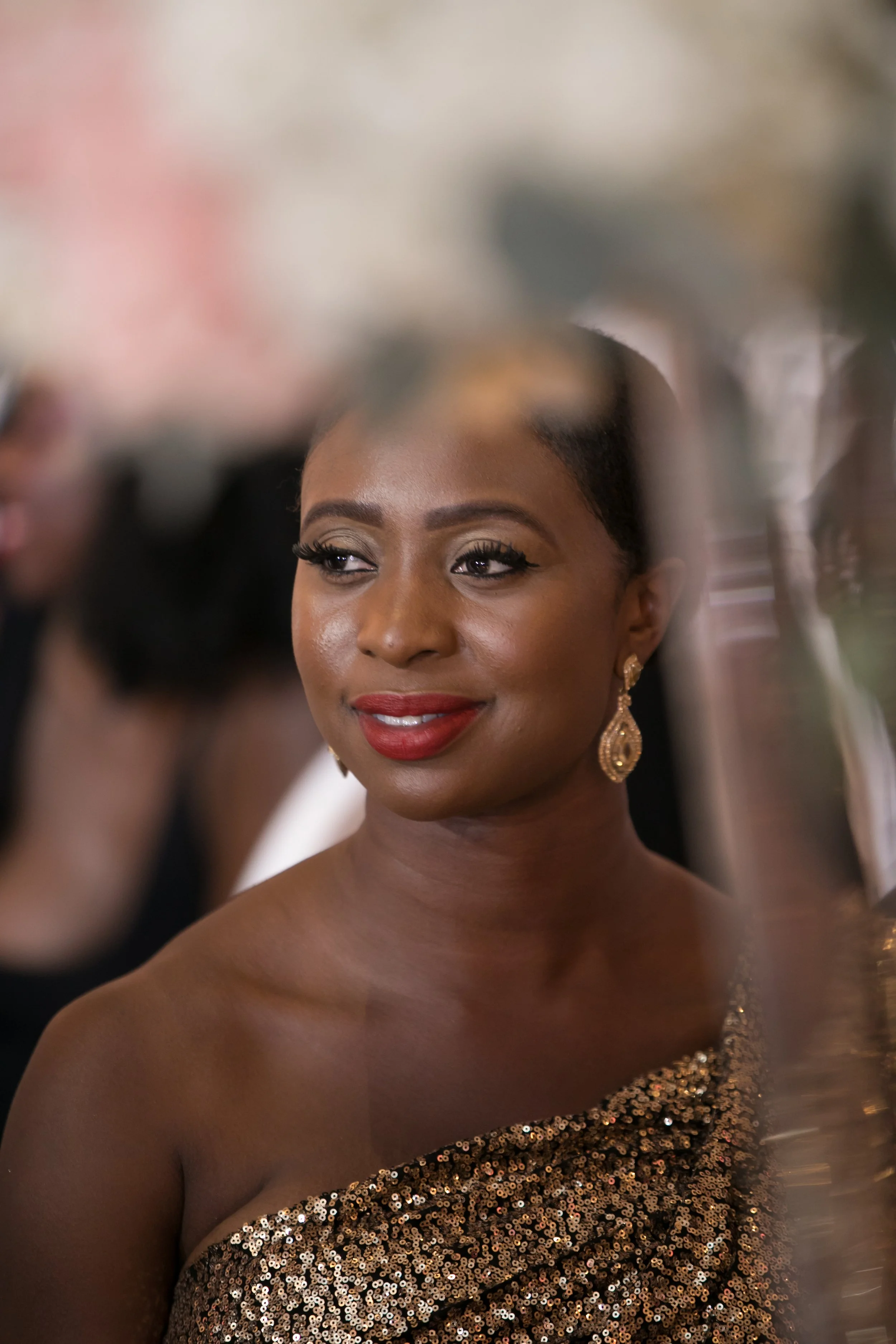 Guest in a gold sequinned one-shoulder gown, close portrait