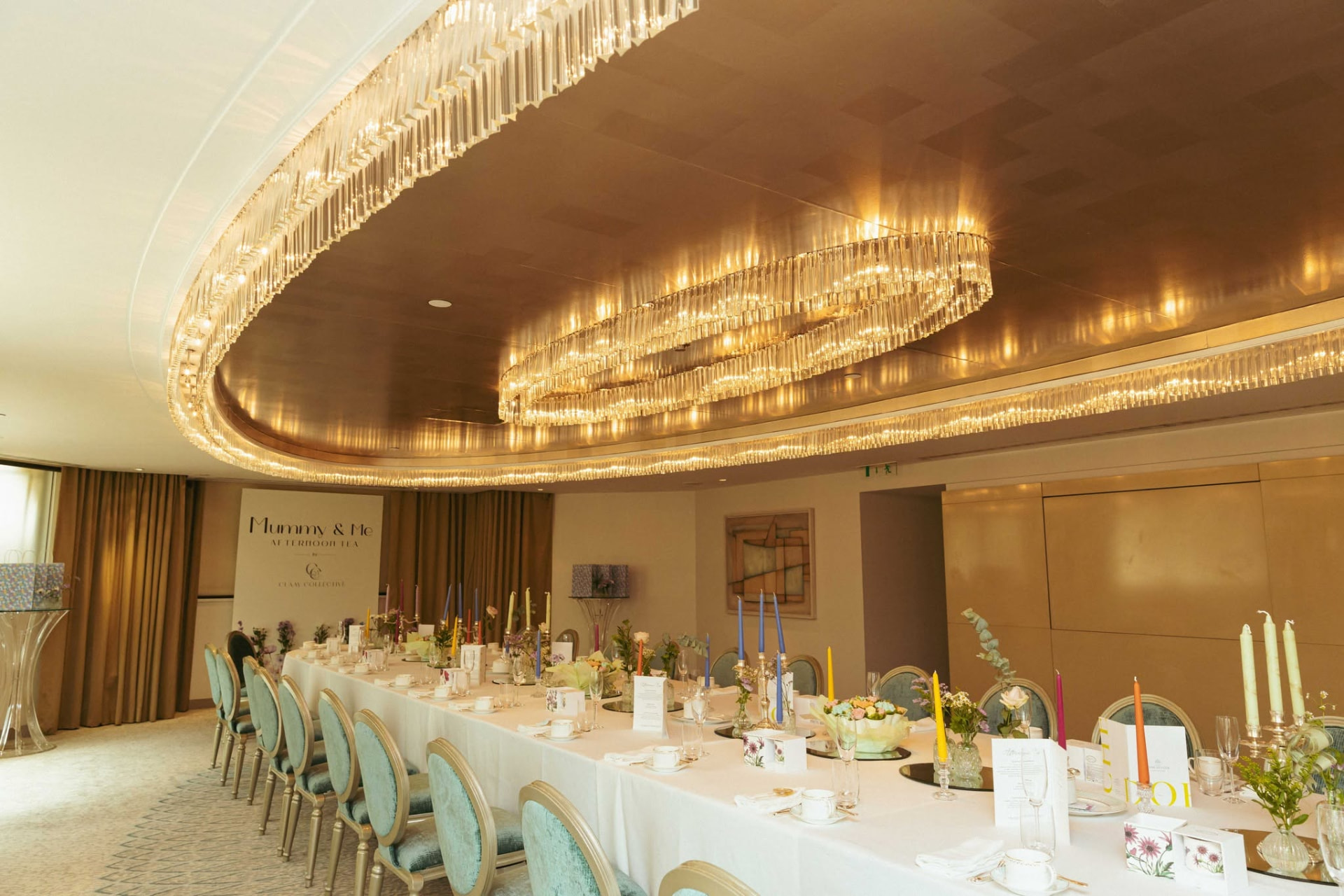 A long white table set beneath a vast oval crystal chandelier in a private room at The Dorchester