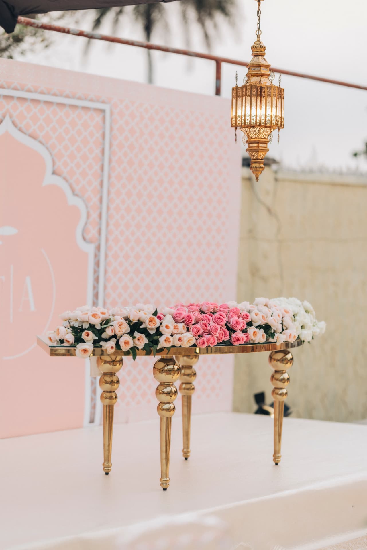 Gilded mirrored table banked with pink and ivory roses beneath a Moorish brass lantern