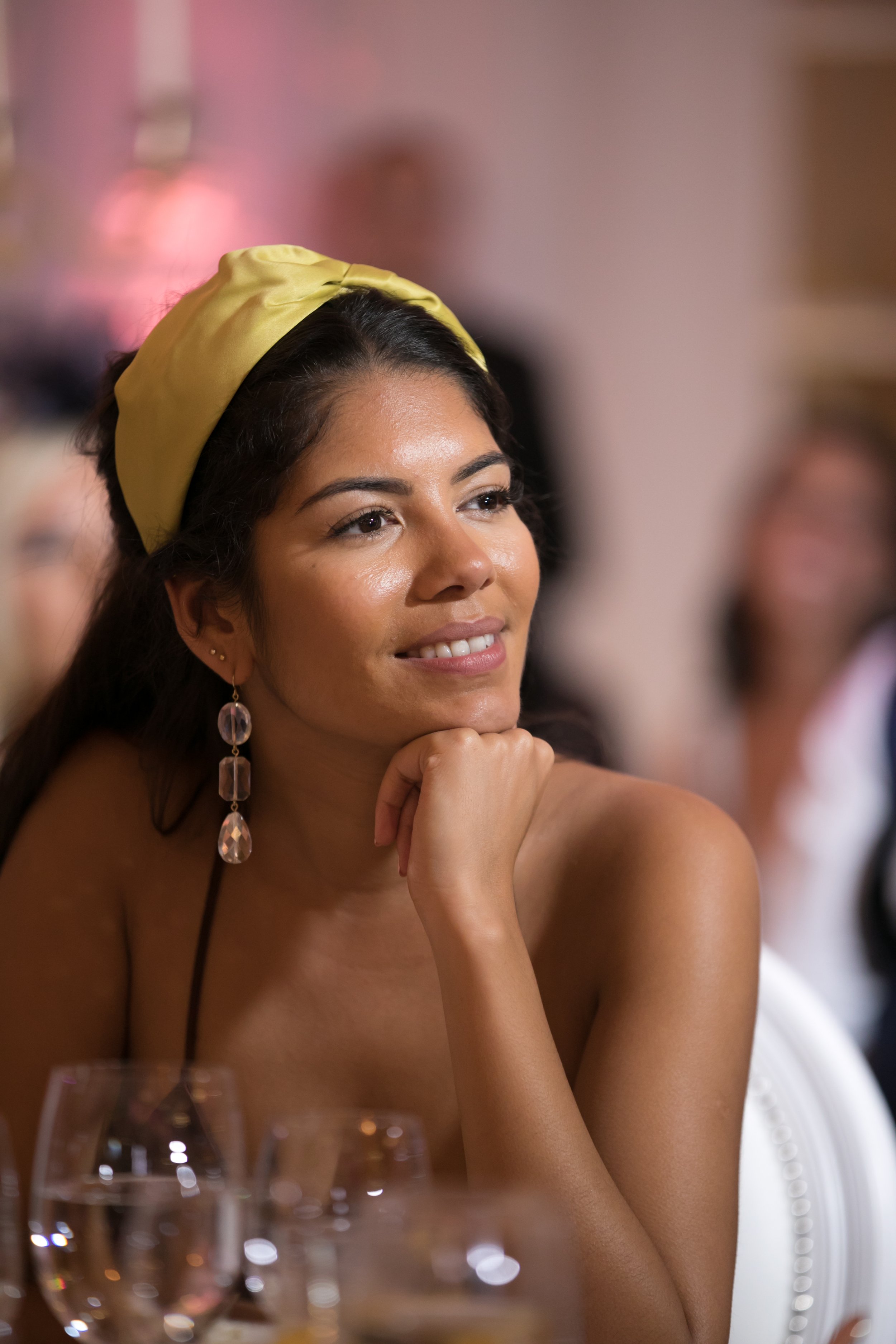Guest in a chartreuse headwrap and statement earrings at the dinner table