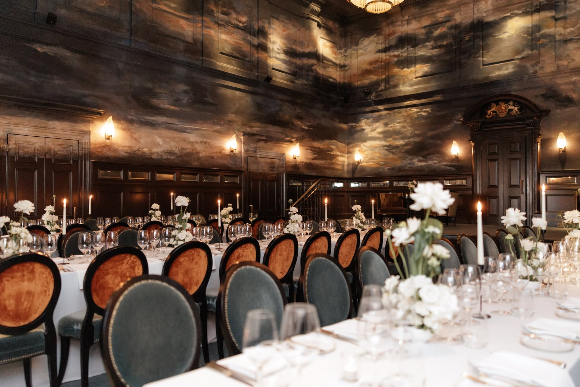 Panelled dining room with painted cloud murals and candlelit tables at Nomad Hotel London