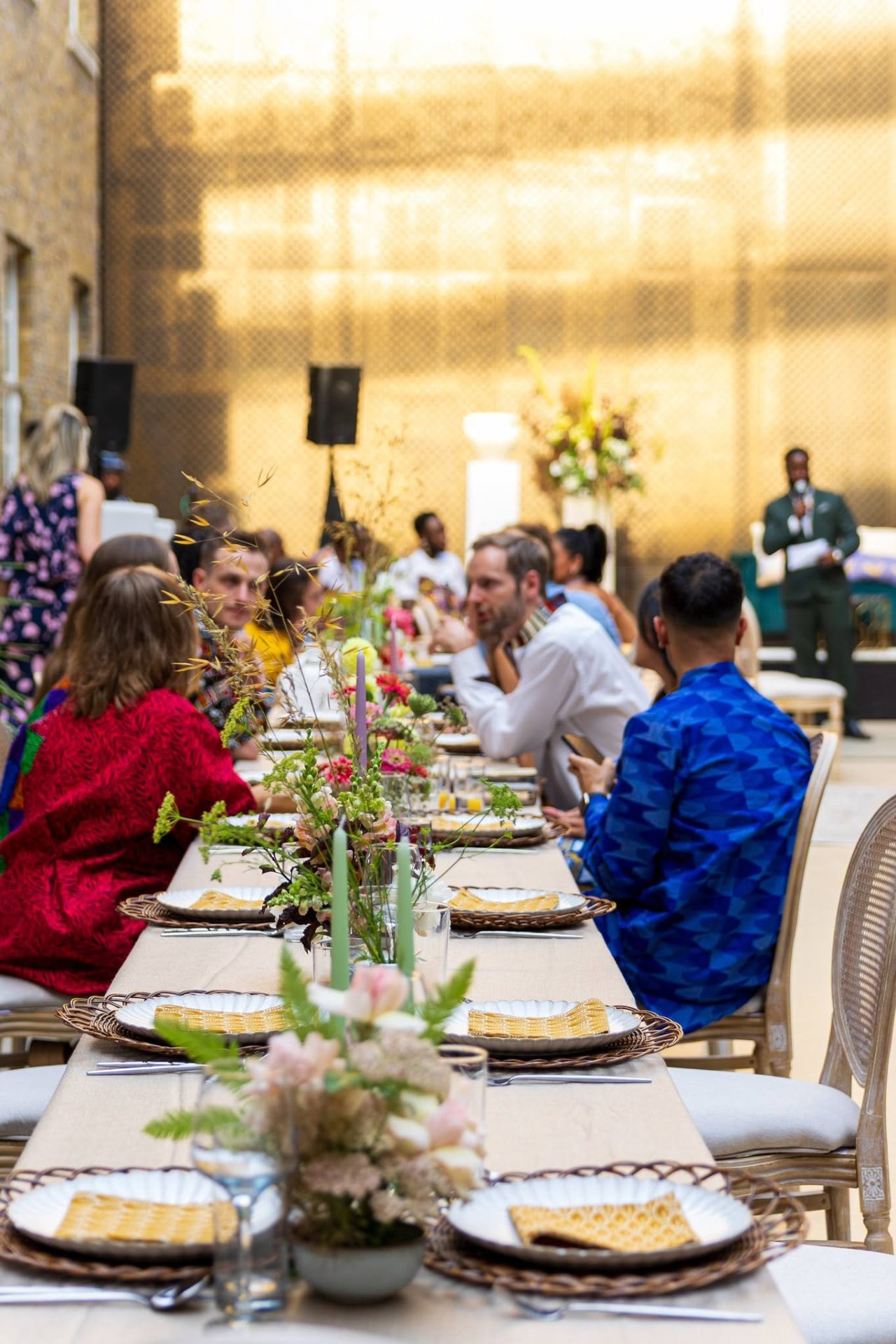 A long table dinner bringing together guests across cultures in a warm golden courtyard
