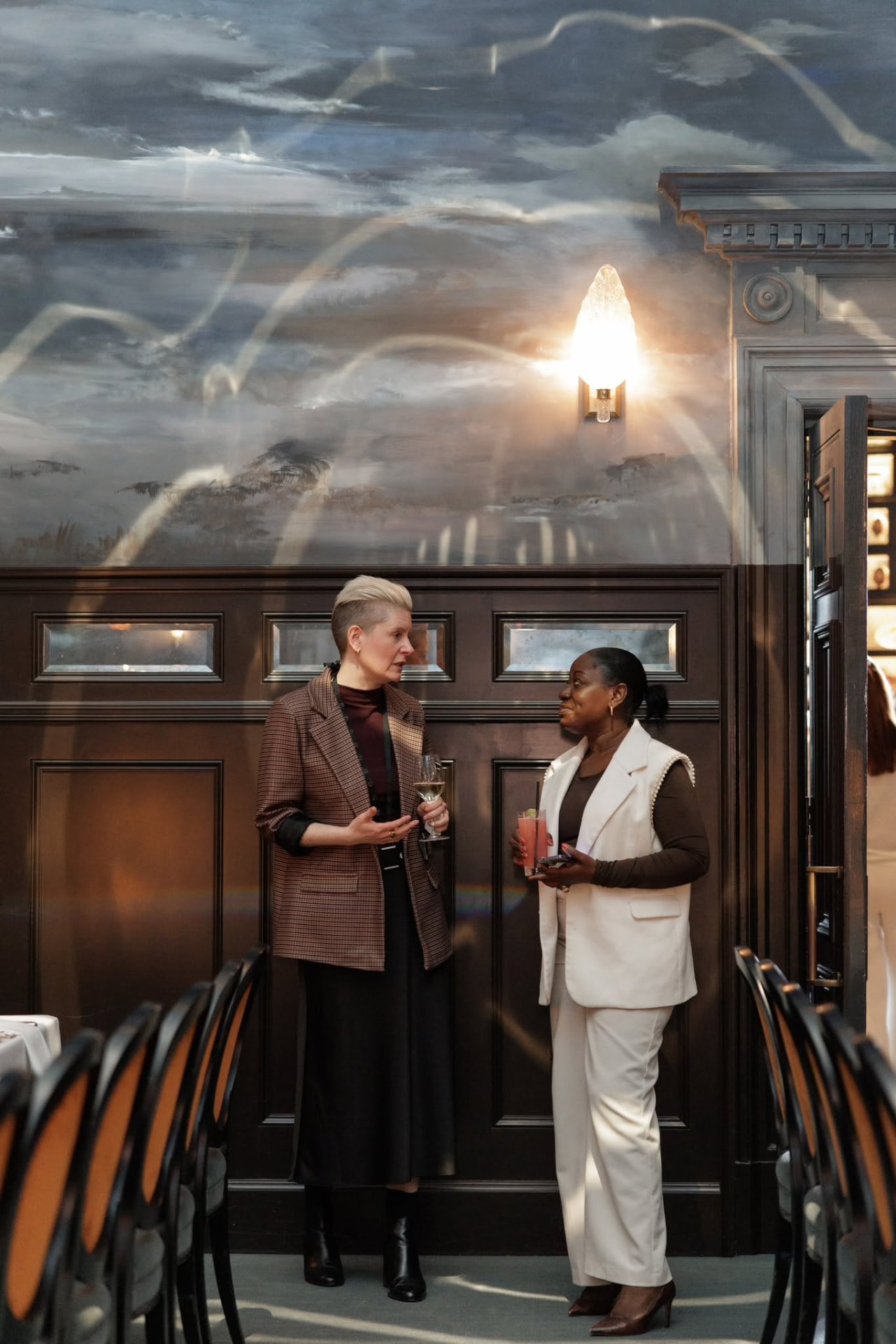Two guests in conversation against panelled walls at Nomad Hotel London