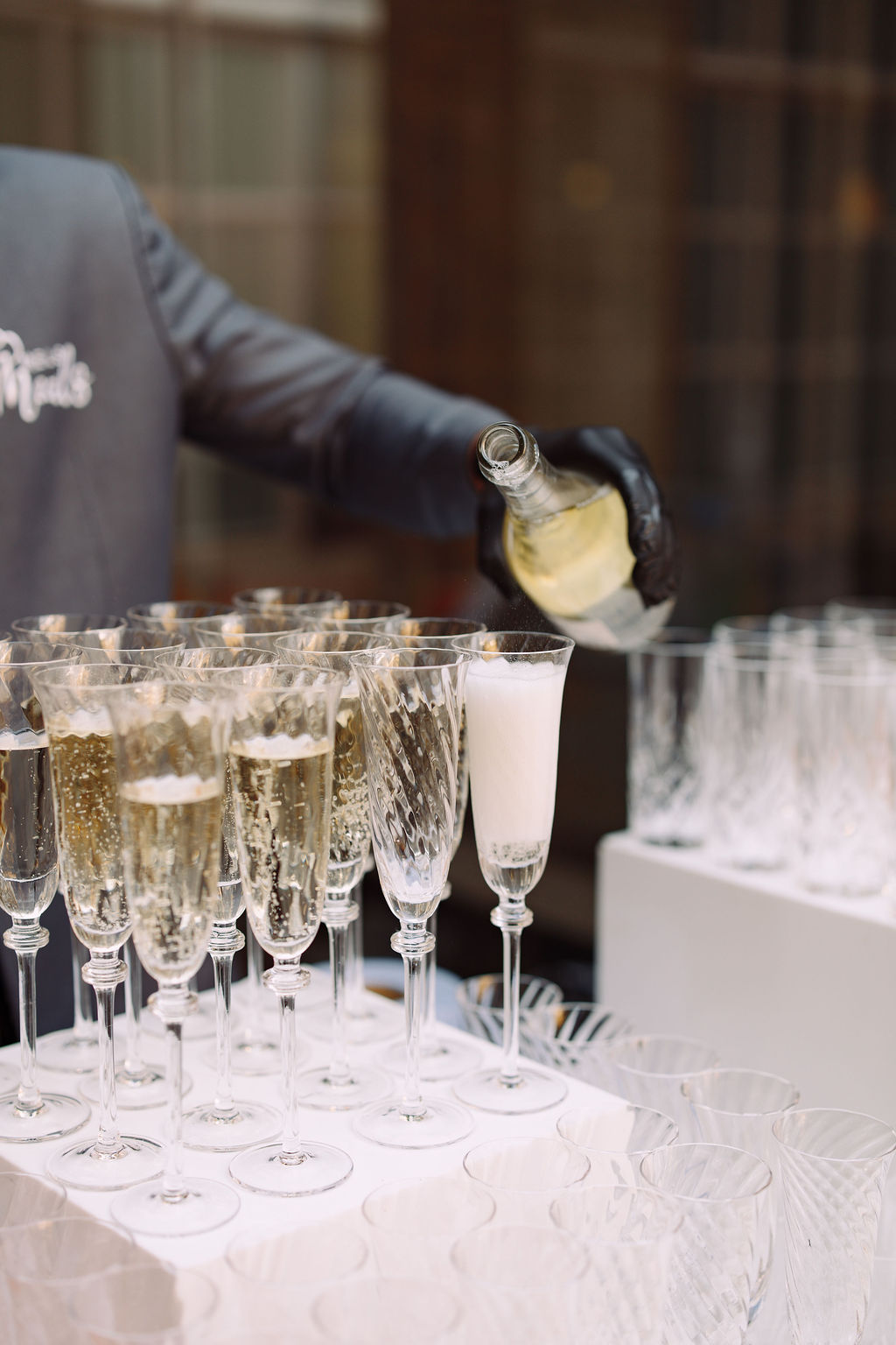 Server in black gloves pouring grower champagne into cut crystal flutes on a white display