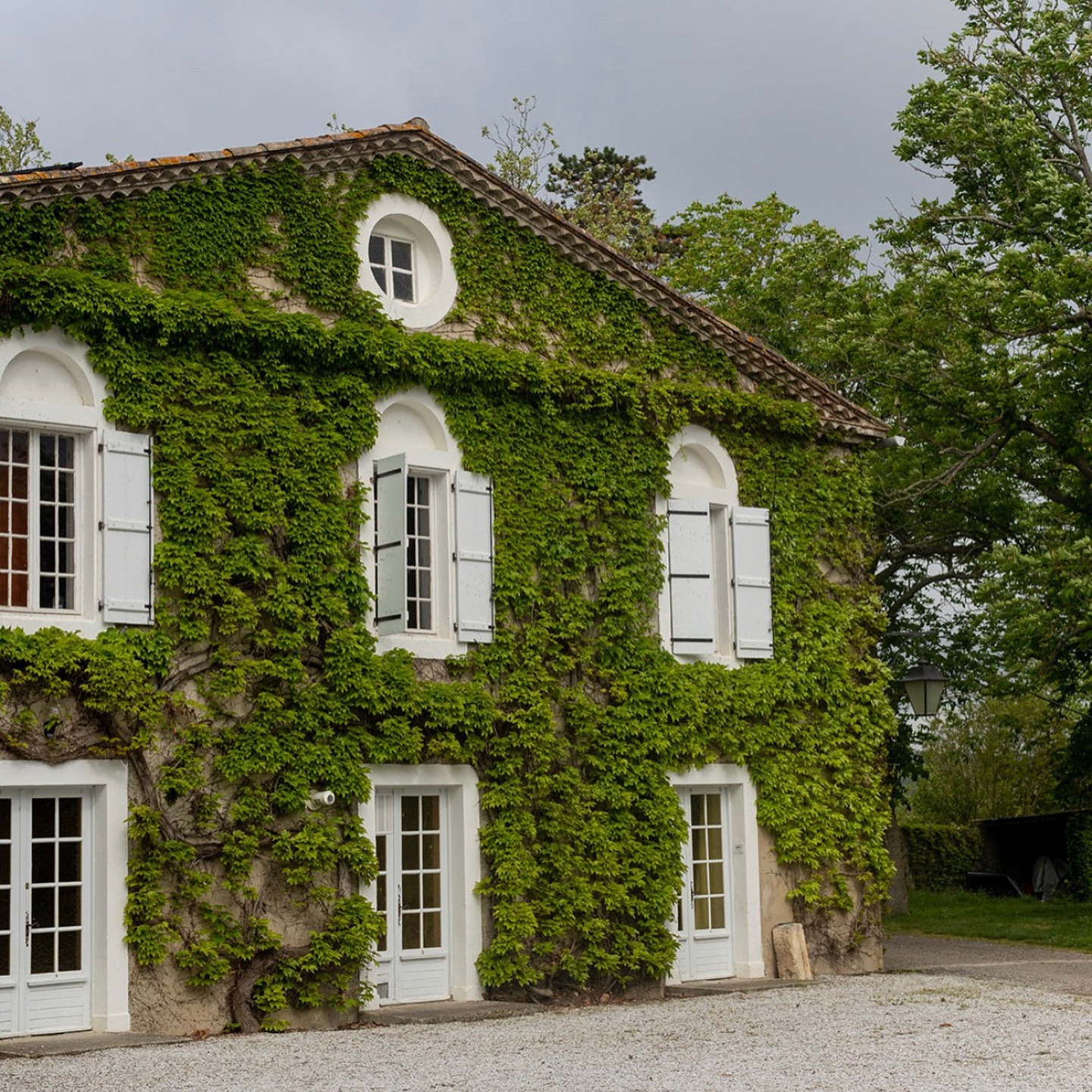 Ivy-covered stone wing of Château Saint Joseph with pale shuttered windows