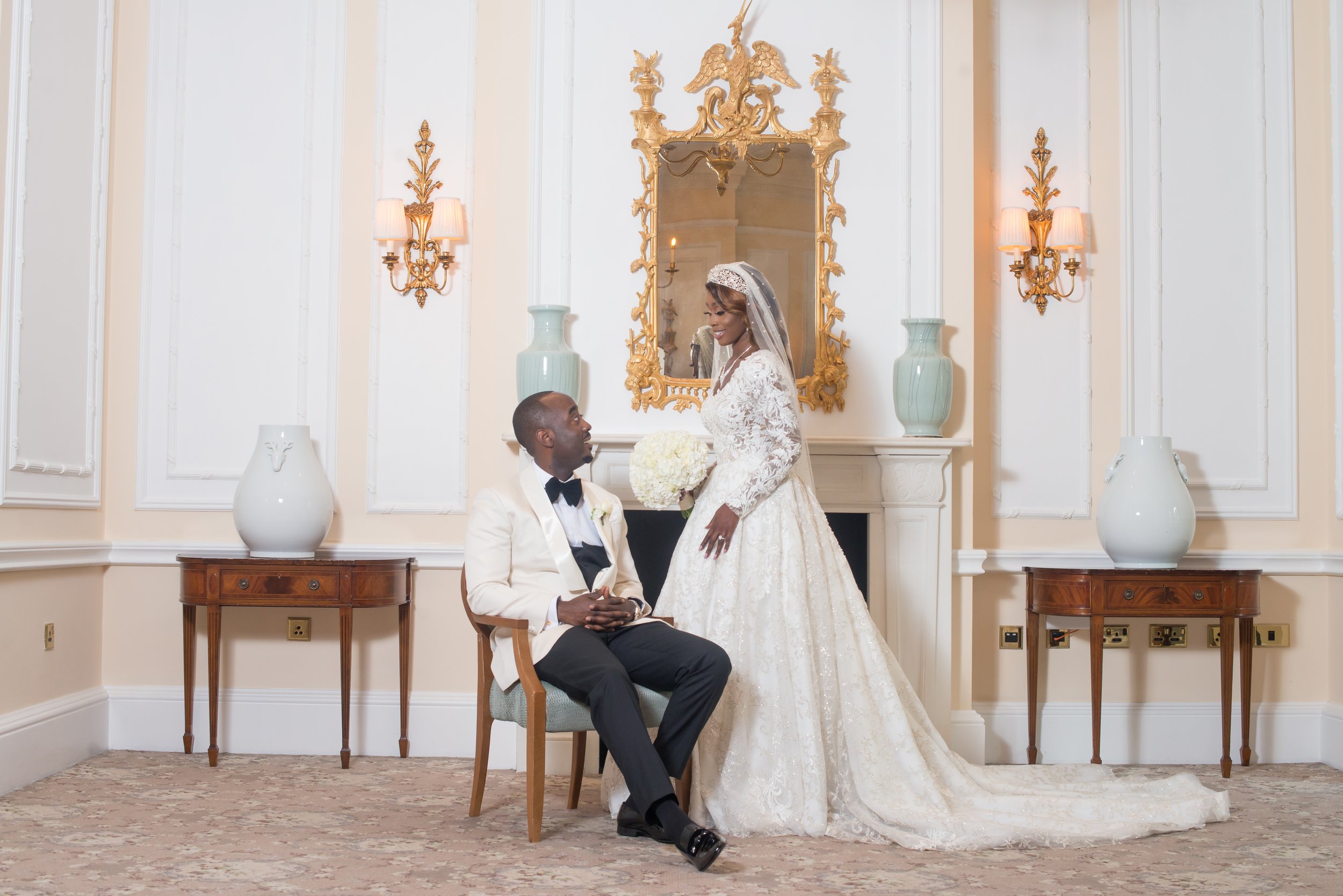 Couple in ivory dinner jacket and lace gown in a mirrored Savoy salon