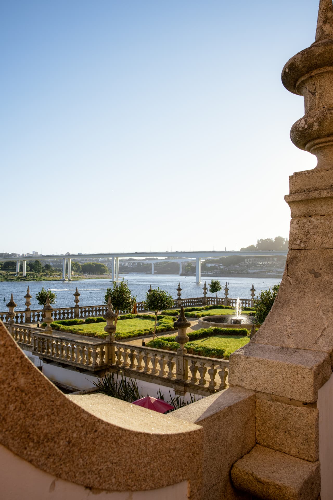 The manicured gardens and stone terraces of Pestana Palácio do Freixo, with the Douro river and bridge beyond
