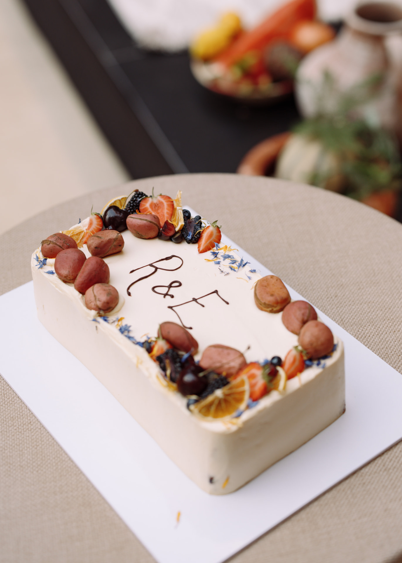 The celebration cake dressed with strawberries, blackberries, cherries, dried orange, kola nuts and scattered blue and yellow petals