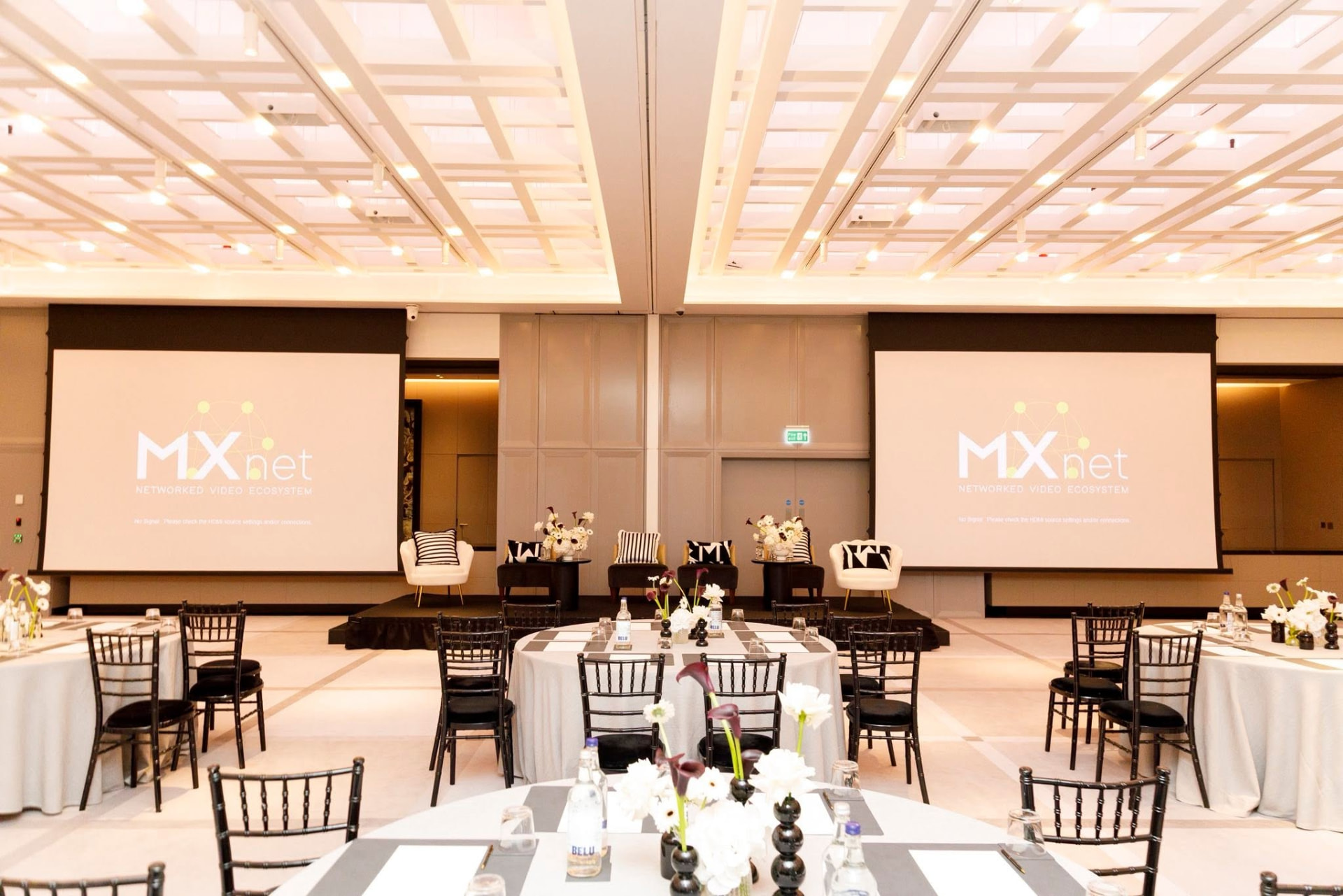 Ballroom set with round tables, black chiavari chairs and twin presentation screens at Hyatt London