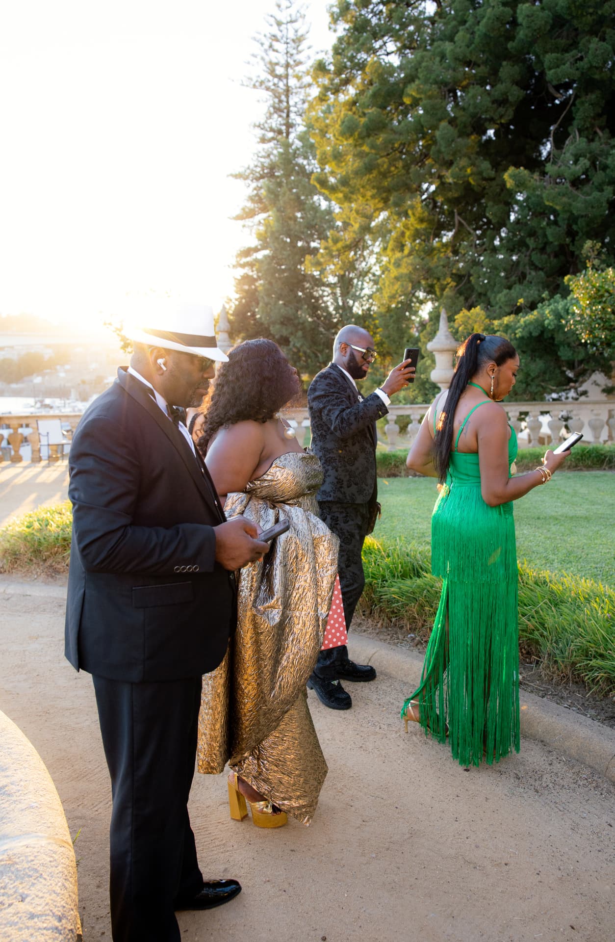 Guests in evening dress on a palace garden path in golden hour light