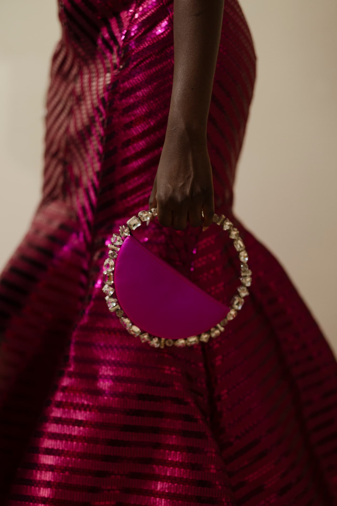 Guest in a fuchsia sequinned gown holding a crystal-framed circular clutch