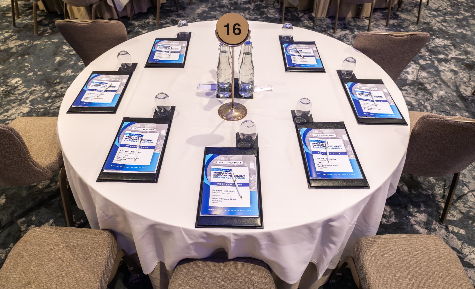 Overhead view of a round conference table dressed with programme books and glassware