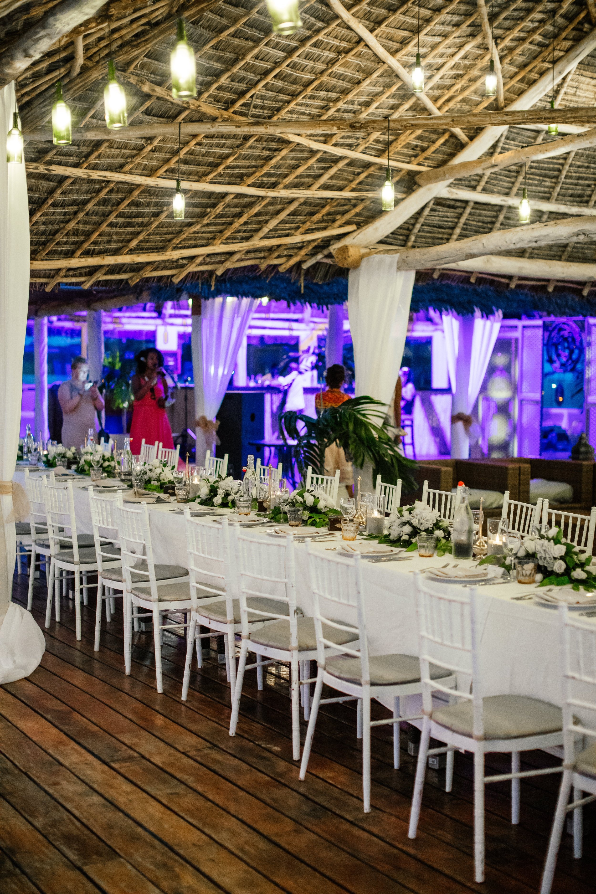 Long dining table set beneath a makuti thatch roof